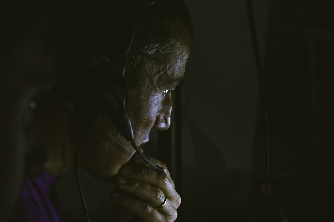 Broadcast director speaking calmly into a headset microphone